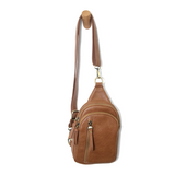 Blending uptown chic with downtown cool, the Skyler sling bag is made in rich vegan cognac brown leather! A convertible strap lends versatility, while a front zip pocket offers practical storage for your necessities. It is the perfect companion for a night out on the town or a fun day trip!