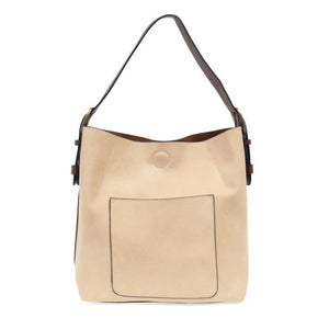 Equally timeless and modern, our best-selling classic hobo is made in rich vegan leather in a beautiful cream color, accented with a coffee brown strap.  This roomy bag, accented with a large front pocket and a snap-in removable brown crossbody, has plenty of room to carry your needs in style.