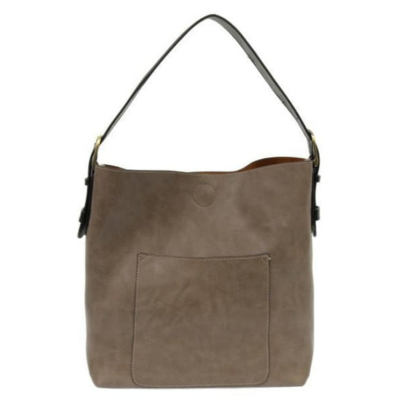 Equally timeless and modern, our best-selling classic hobo is made in rich vegan leather in mushroom accented with a black strap.  This roomy bag, accented with a large front pocket and a snap-in removable crossbody, has plenty of room to carry your needs in style