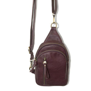 Blending uptown chic with downtown cool, the Skyler sling bag is made in rich vegan wine-colored leather! A convertible strap lends versatility, while a front zip pocket offers practical storage for your necessities. It is the perfect companion for a night out on the town or a fun day trip!  8" h x 5.5" w  x 2.25" d