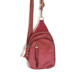 Blending uptown chic with downtown cool, the Skyler sling bag is made in beautiful holly berry pink velvet! A convertible strap lends versatility, while a front zip pocket offers practical storage for your necessities. It is the perfect companion for a night out on the town or a fun day trip!  8" h x 5.5" w  x 2.25" d