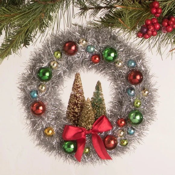 This brightly colored red, green, and blue beaded tinsel wreath with multi-colored bottle brush trees in the center will add Merry and Bright to your holiday!  Materials: Tinsel, beads, ribbon, and bottle brush trees with glitter.  Dimensions: 6.5