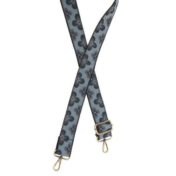 You'll love changing up the style of your purse with one of our guitar straps! This blue woven strap has teal/green and purple daisies going down it - so cute! The back of the strap is solid black.  35