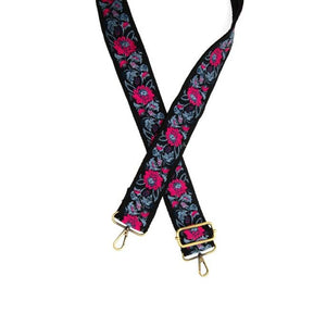 Give your bag some personality with this embroidered guitar strap in a beautiful floral pattern in a lovely black, periwinkle &amp; blue with a hot pink flower design.  2" wide  35-54" adjustable length  Brass plated hardware  100% Cotton