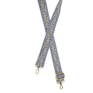 You'll love changing up the style of your purse with one of our guitar straps! This white strap has a blue stripe on the outside of the strap with a pretty blue and black vine scrolling vine pattern in the center.  35"-54" adjustable length  1.5" wide  Brass plated hardware