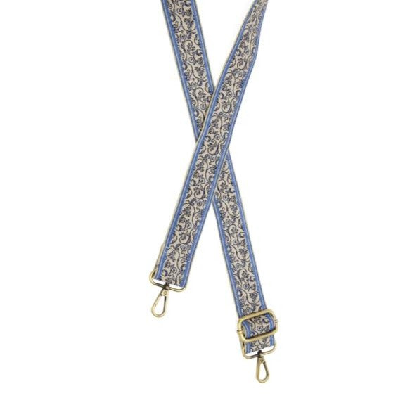 You'll love changing up the style of your purse with one of our guitar straps! This white strap has a blue stripe on the outside of the strap with a pretty blue and black vine scrolling vine pattern in the center.  35