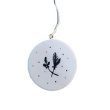 "Merry Christmas" Porcelain Heart Ornament has a bird on a branch with snow falling around it. On the back is two sprigs of evergreen with berries on a snowy background.  2" Dia