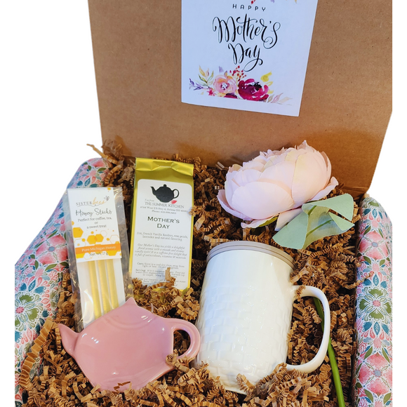 If mom LOVES tea, send her a tea box today! Our Happy Mother's Day Tea Box has our popular Basket Weave Tea Infuser Mug with a grey silicone lid that she'll be able to brew our caffeine free Mother's Day Tea in. We've also included a Pink Teapot Bag/Spoon Holder and some Honey Sticks.  She'll love the Pretty Silk Peony Stem to put in her favorite vase. All of this is packed in crinkle and wrapped wup in a pink, green, blue and white floral patterned tissue and tied in a bow.  If you'd like us