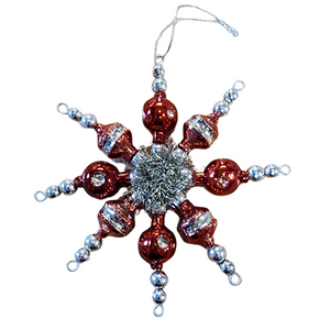 This retro-inspired ornament features red hand-crafted glass beads threaded together to form a star and&nbsp;a tinsel center for some yesteryear charm!

1" H x 6 1/2" Dia

Glass&nbsp;