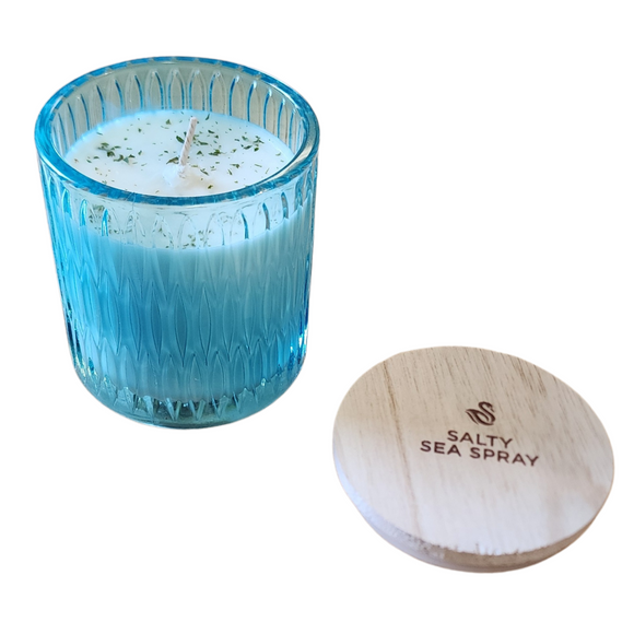 You'll love our newest cathedral glass tumbler! This salty sea spray scent has been poured into a pretty blue patterned glass and comes with a wooden lid.

Escape to the ocean! The wild surf crashes the shore through a haze of sunshine and salty air where seagrass, key lime and summer musk co-mingle together with the ozonic, watery notes of an ocean mist. Feel the ocean spray on your face!

Filled with 6.5 oz. of American Soybean WaxTM. Measures 3.25