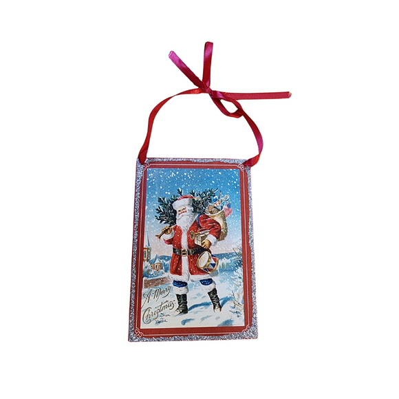 Bring a little nostalgia to your holiday decor this year with this rectangle shaped vintage ornament that has Santa carrying a Christmas tree with his bag of toys and a trumpet and toy drum. Below it says 