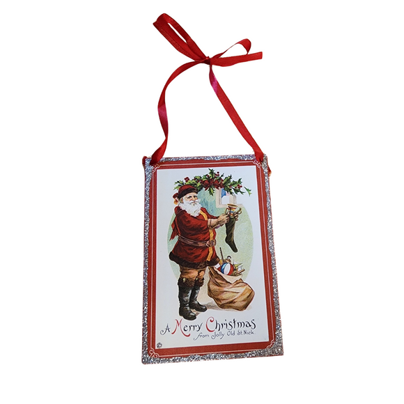 Bring a little nostalgia to your holiday decor this year with this vintage rectangle shaped ornament that has Santa filling the stockings! It has silver glitter on the outside border and a red ribbon to hang it with.

6