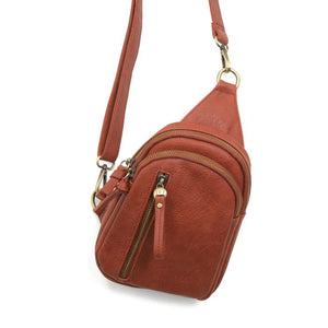 Blending uptown chic with downtown cool, the Skyler sling bag is made in rich spice colored vegan leather! A convertible strap lends versatility, while a front zip pocket offers practical storage for your necessities. It is the perfect companion for a night out on the town or a fun day trip!   8" h x 5.5" w&nbsp; x 2.25" d