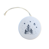 "Walking in a winter wonderland" Porcelain Heart Ornament has two pine trees on the left with a person walking their dog to the right as snow is falling all around. On the back are three pine trees under the stars and moon with snow all around.  2 1/2" Dia