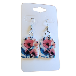 You will love these lightweight, trendy polymer watercolor floral arched earrings! Pink. red and coral flowers with blue accents embellish the white background create a stunning design! The earring hooks are comfortable and easy to wear and coated with a resin layer to give them a pretty shine and finished look. The hooks are made of high-quality, strong/durable stainless steel, which is hypoallergenic and nickel-free. *&nbsp;

This versatile earring design would accompany any outfit, from casual to dressed