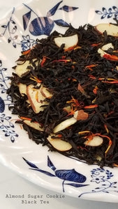black tea leaves on a blue and white floral plate.  Has almond slices and red and yellow petals
