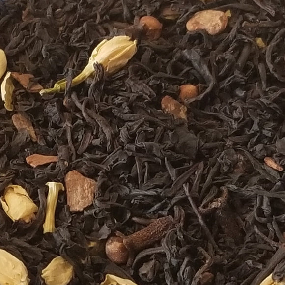 black tea leaves on a blue and white floral pate. has cloves, jasmine petals  and cinnamon in the tea