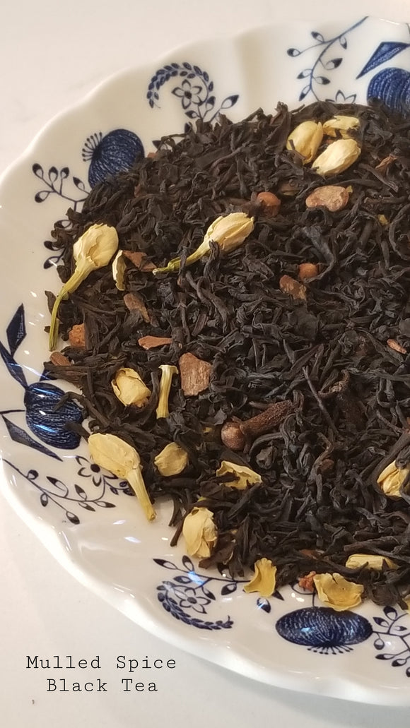 black tea leaves on a blue and white floral pate. has cloves, jasmine petals  and cinnamon in the tea