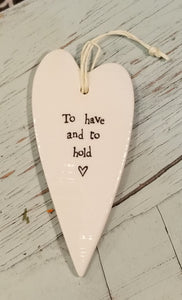 a porcelain white heart shaped ornament with a white cord to hang with the words "to have and to hold"