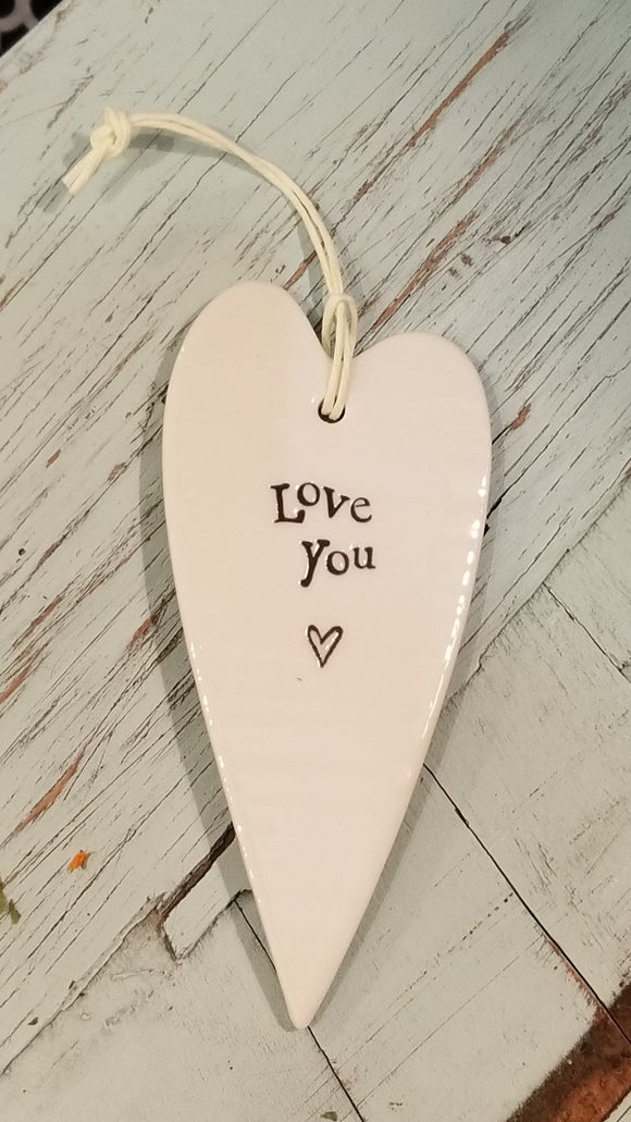 a porcelain white heart shaped ornament with a white cord to hang with the words 