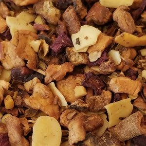 Our roasted almond blend fruit tea: fruit tea blend has apple pieces, planed almonds, sliced almonds, cinnamon pieces & beetroot. It is sitting on top of a white plate with a blue onion pattern on it.