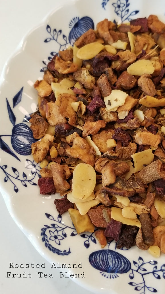 Our roasted almond blend fruit tea: fruit tea blend has apple pieces, planed almonds, sliced almonds, cinnamon pieces & beetroot. It is sitting on top of a white plate with a blue onion pattern on it.