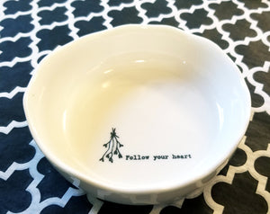 This little trinket bowl will brighten your day!  This white porcelain bowl has a wobbly finished trim. Inside the bowl, it has branches with hearts on the bottom of them tied with a ribbon and to the right, the sweet sentiment: "Follow Your Heart" in black writing.  1/4" H x 4" Dia