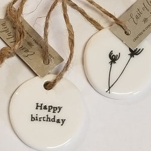 These little porcelain tags are as cute as can be. With a sentiment on one side and a branch with flowers on the other, they have a cord that can be put on a bag or put into a card to give to someone.  1 1/4" Dia