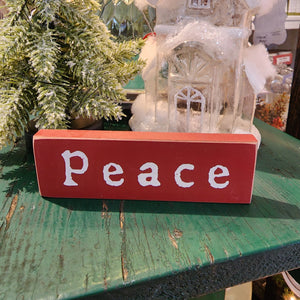 This "Peace" mini sign features a deep red finish with natural wood edges. This freestanding wood block will dress up shelves and tabletops for the holidays!  1.5" h x  5" w x 1/2" d