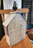 This fun birdhouse has a distressed finish with metal finishes on the front and a metal roof up top.  On top o the roof, there is a black wooden finial with a ring to easily hang your birdhouse if you wish!  The side of it has an opening through to the other side. 6"W x 3.5" D x 12" H
