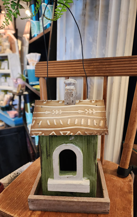 This wooden birdhouse has a pretty green finish with a cute window with white trim on the front.  The base is wood, and the roof is a distressed brown metal with a wooden finial on top.  There is a black wire on top for easy hanging.  5.5