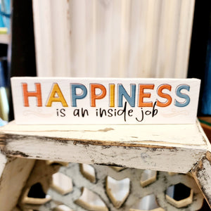 This a great reminder to put out to see every day!  This mini sign has a white background and the words "HAPPINESS is an inside job" written on it ("Happiness" is in orange, yellow, and turquoise capital letters, and "is an inside job" is in black).  It has two scrolls on either side of "is an inside job" along the bottom.  Wood  Depth: 0.4375" Width: 6" Height: 1.5"