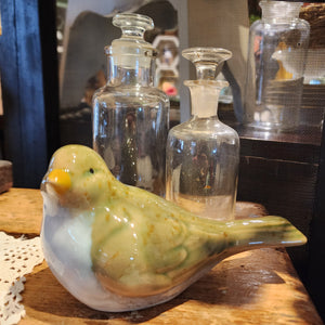 This stoneware green bird will add some sweetness to your decor!  The top is a green glaze with brown speckles scattered throughout.  The breast of the bird has a white glaze with hints of blue. Pair it with our stoneware bird looking down! Stoneware  5.75" W x 2.75" D  x 3.5" H
