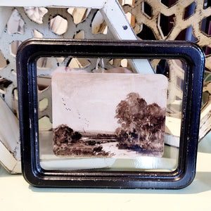 What a fun picture to display on your wall, bookcase, or picture frame! It has a distressed black frame with a vintage reproduction landscape floating in the frame. The black and white watercolor picture has a river with tall trees on the right side and smaller trees on the left.   8-1/4"W x 7"H