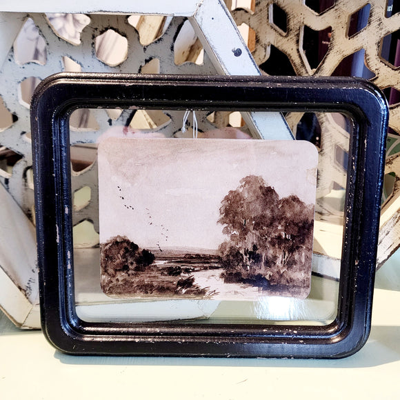 What a fun picture to display on your wall, bookcase, or picture frame! It has a distressed black frame with a vintage reproduction landscape floating in the frame. The black and white watercolor picture has a river with tall trees on the right side and smaller trees on the left.   8-1/4