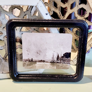 What a fun picture to display on your wall, bookcase, or picture frame! It has a distressed black frame with a vintage reproduction landscape floating in the frame. The black and white watercolor picture has sailboats and a small lighthouse.   8-1/4"W x 7"H