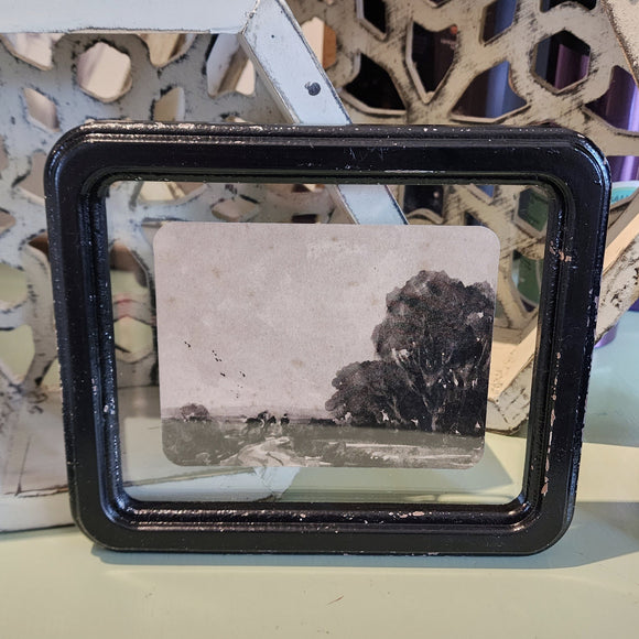 What a fun picture to display on your wall, bookcase, or picture frame! It has a distressed black frame with a vintage reproduction landscape floating in the frame. The black and white watercolor picture has a road with a horse with a rider and another figure walking beside with trees off to the right.   8-1/4