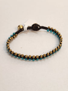 We love this split turquoise and brass beaded bracelet! The beads are woven onto a brown cord and it has two brass bell accents to hook the loop on the end to wear the bracelet around your wrist. (The bells do give a little jingle as you wear it around ~ so fun!)  The first bell is approximately 6.5" and the second is approximately 7"  Made in Thailand