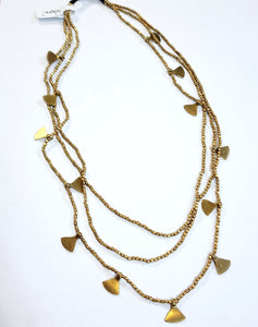 This brass layered necklace is beautifully done!  Three strands of brass beads are all attached to a brown cord with a brass bell toggle. The longest strand has brass triangle charms hanging from it. Our Nyra necklace will be one of your favorite pieces to put on!  22" long  Handmade by a young designer and team of artists in Northern India