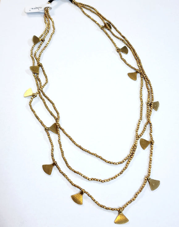 This brass layered necklace is beautifully done!  Three strands of brass beads are all attached to a brown cord with a brass bell toggle. The longest strand has brass triangle charms hanging from it. Our Nyra necklace will be one of your favorite pieces to put on!  22