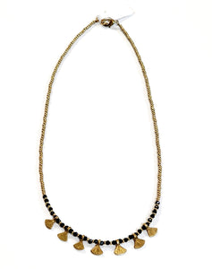 This gold beaded necklace with glass black beads and has 7 gold triangle shapes hanging from the bottom. It is pretty to wear alone but looks great layered with one of our longer brass necklaces!  Handmade by a young designer and team of artists in Northern India.  17"-18" Adjustable necklace 