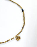 A beautiful 34" layering necklace with brass beads accented with several sets of three glass blue beads, making a beautiful pattern around the necklace.  In between the blue glass beads are brass circle charms.  Handmade by a young designer and team of artists in Northern India.  17" drop    