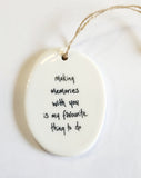 We love our porcelain ornaments because they are perfect for gift-giving! This oval ornament says, "Making memories with you is my favourite thing to do" on one side. The other side has a grey background with a mountain scene with stars and the moon in the sky, all in white.  Dimensions: 2" W x 2 3/4" H