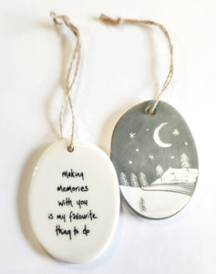 We love our porcelain ornaments because they are perfect for gift-giving! This oval ornament says, "Making memories with you is my favourite thing to do" on one side. The other side has a grey background with a mountain scene with stars and the moon in the sky, all in white.  Dimensions: 2" W x 2 3/4" H