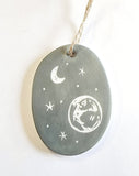 We love our porcelain ornaments because they are perfect for gift-giving! This oval ornament says, "I may not always be with you, but I will always be there for you" on one side. The other side has a grey background with stars, a crescent moon, and planet earth in the sky.  Dimensions: 2" W x 2 3/4" H