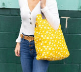 These sweet daisies on a yellow background make such a cute & happy print! All of our bags are printed on recycled canvas with eco-friendly pigment inks. Our canvas totes are soft yet durable, and an easy carry-all. Not just for the market. This streamlined tote features an interior strap and hooks to attach our pouches. Printed on recycled canvas with eco-friendly pigment inks. Can we say hooray?  Dimensions: 12" x 16" x 4"     Strap Drop: 6.25". Made in India