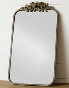 This mirror is a romantic one!  We love the simplicity of it and the beautiful distressed metal florals at the top.   32" H x 18" W x 1.5" D  Iron, Glass & Wood  Available in-store only.