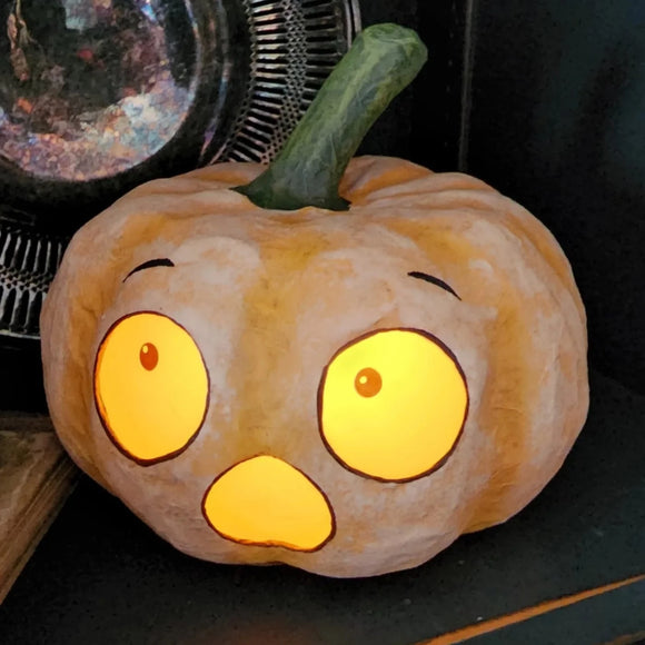 EEK! This little orange pumpkin has heard more than a bump in the night!  Made of paper mache, this pumpkin has printed paper inserts for his eyes and mouth. Put a battery-powered light underneath so that his eyes glow in the dark! Paper mâché, velum.  Approximately 5.5