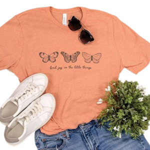 We're smitten with this butterfly tee!  It s the softest shade of melon with three putter flies across the chest, and below it says "find joy in the little things" written in cursive.