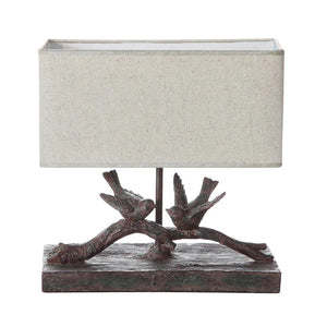 Bring garden-inspired style to your home with this bird lamp! The resin base features a tree branch with two birds perched atop it. Intricate carvings bring a lifelike quality to the piece, while the dark brown finish contrasts the linen-colored rectangular shade.   12-1/2"L x 5" D x 12"H   Light bulb not included (40 Watt Bulb Maximum).